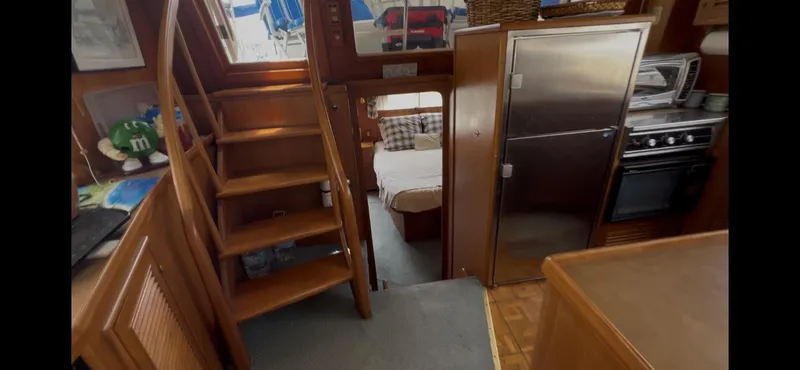 Slide: The Image of Interior of 1988 Offshore Yachts 48 CPMY, featuring stairs, kitchen, and bedroom. - 11