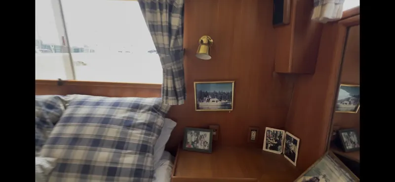Slide: The Image of Cozy cabin interior of 1988 Offshore Yachts 48 CPMY with plaid bedding and framed photos. - 14