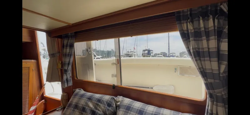 Slide: The Image of Interior view of 1988 Offshore Yachts 48 CPMY with plaid curtains and marina backdrop. - 16