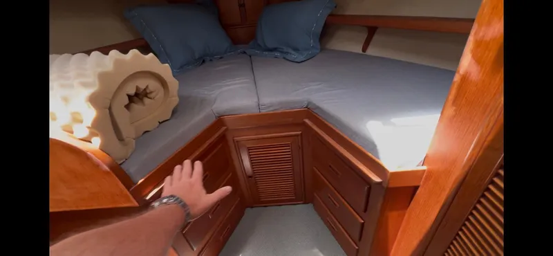 Slide: The Image of 1988 Offshore Yachts 48 CPMY cabin with wooden storage and blue bedding. - 23