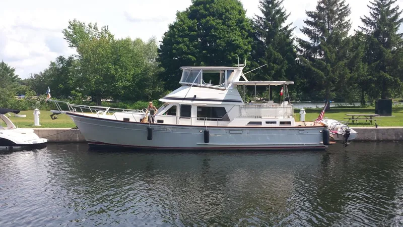 Slide: The Image of 1988 Offshore Yachts 48 CPMY docked on a calm waterway with lush greenery. - 33