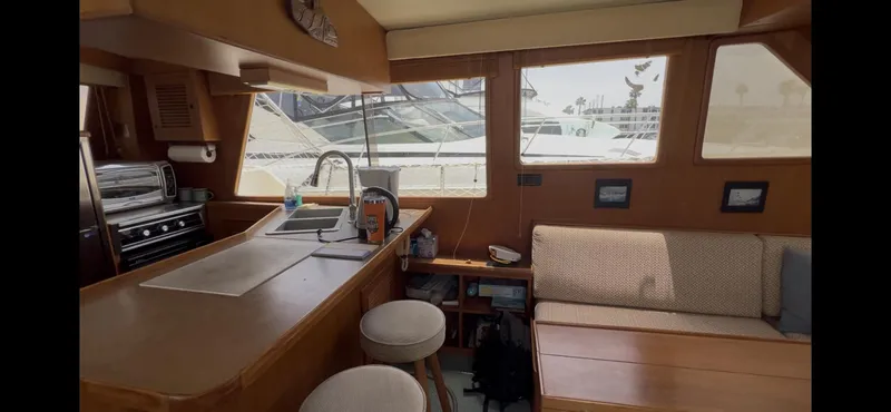 Slide: The Image of Interior of 1988 Offshore Yachts 48 CPMY, featuring kitchen and seating area with large windows. - 4