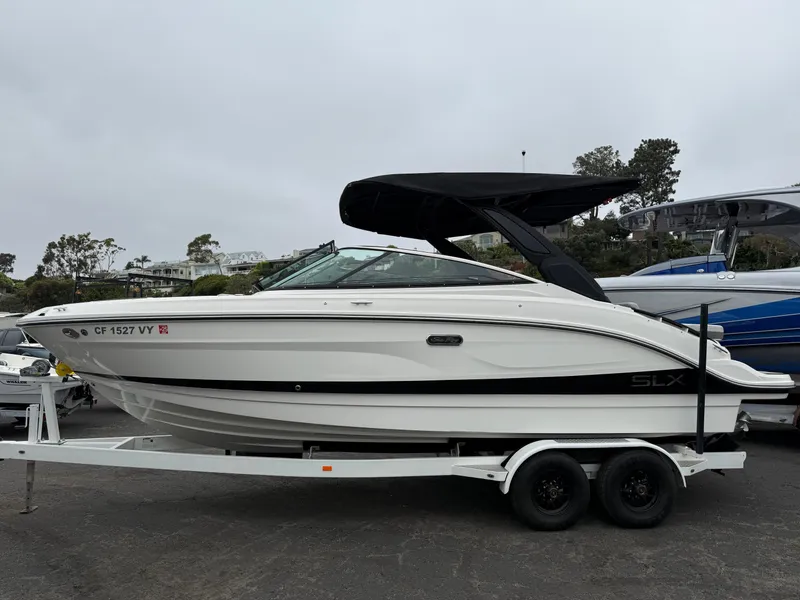 The Image of 2024 Sea Ray SLX 260 boat on trailer, featuring sleek design and black canopy. - 0