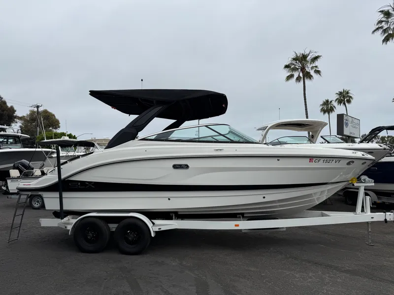 Slide: The Image of 2024 Sea Ray SLX 260 boat on trailer, parked outdoors with palm trees in background. - 1