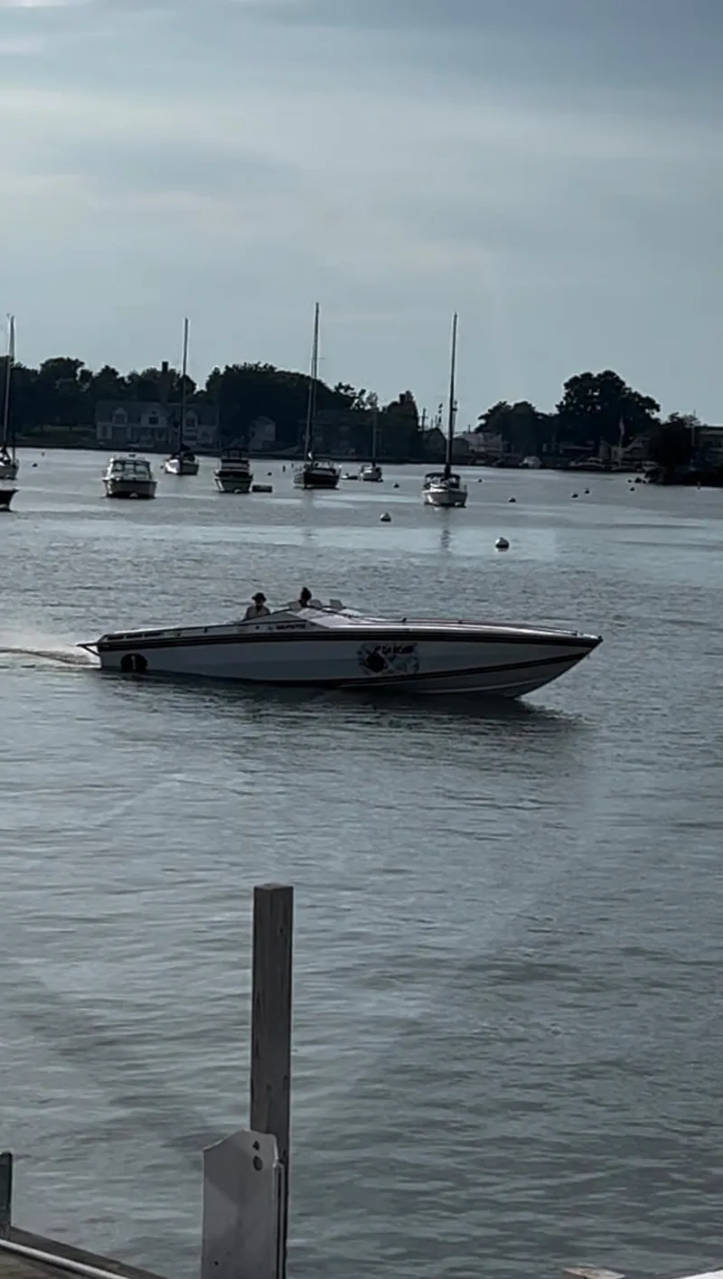 Slide: The Image of 1987 Cigarette 38 Top Gun speedboat on calm water with distant sailboats. - 7