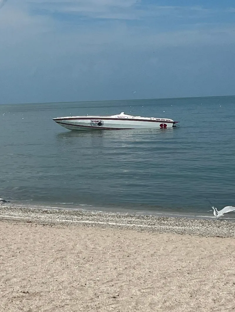 Slide: The Image of 1987 Cigarette 38 Top Gun boat on calm sea near sandy beach. - 8