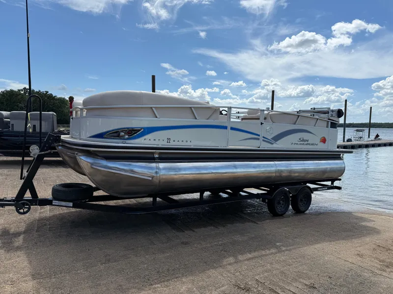 Slide: The Image of 2011 Sun Tracker Regency Party Barge 22 on trailer by a lake under blue sky. - 2