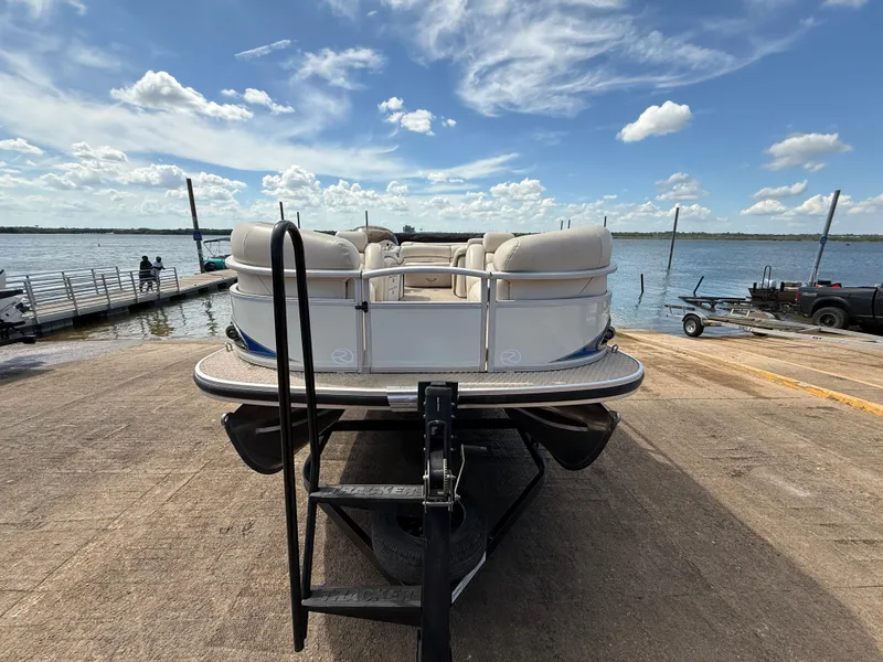 Slide: The Image of 2011 Sun Tracker Regency Party Barge 22 on trailer by a lake under blue sky. - 22