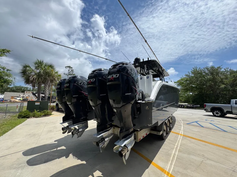 Slide: The Image of 2020 Invincible 40 Catamaran with powerful outboard engines, parked outdoors under a cloudy sky. - 13