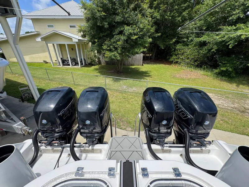 Slide: The Image of Four powerful outboard motors on a 2020 Invincible 40 Catamaran, parked near a house. - 49