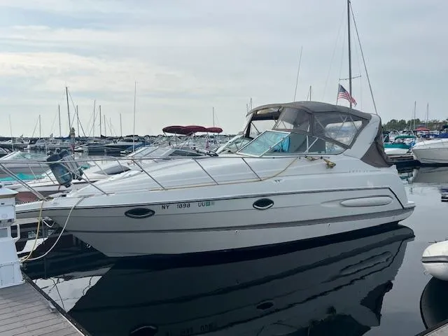 The Image of 1999 Maxum 2800SCR boat docked at marina, featuring sleek design and covered cockpit. - 1