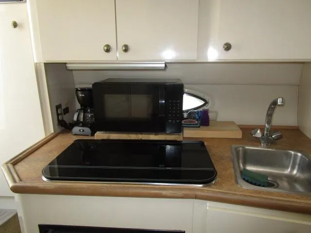 Slide: The Image of 1999 Maxum 2800SCR boat kitchenette with microwave, stove, sink, and cabinets. - 11