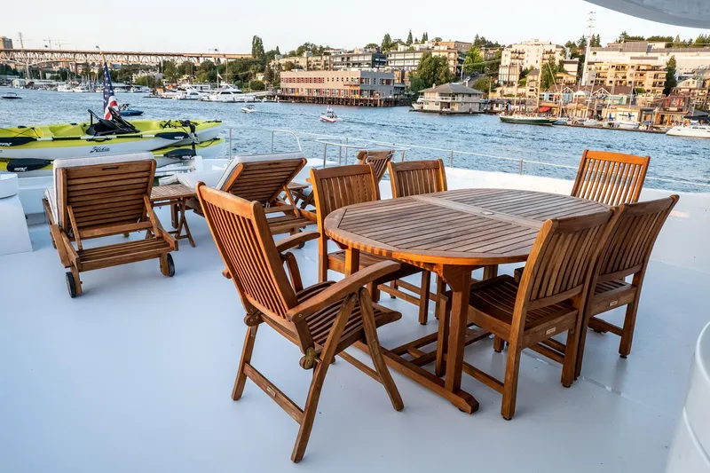 Slide: The Image of Deck of 1993 Queenship LRC yacht with wooden dining set and waterfront view. - 7
