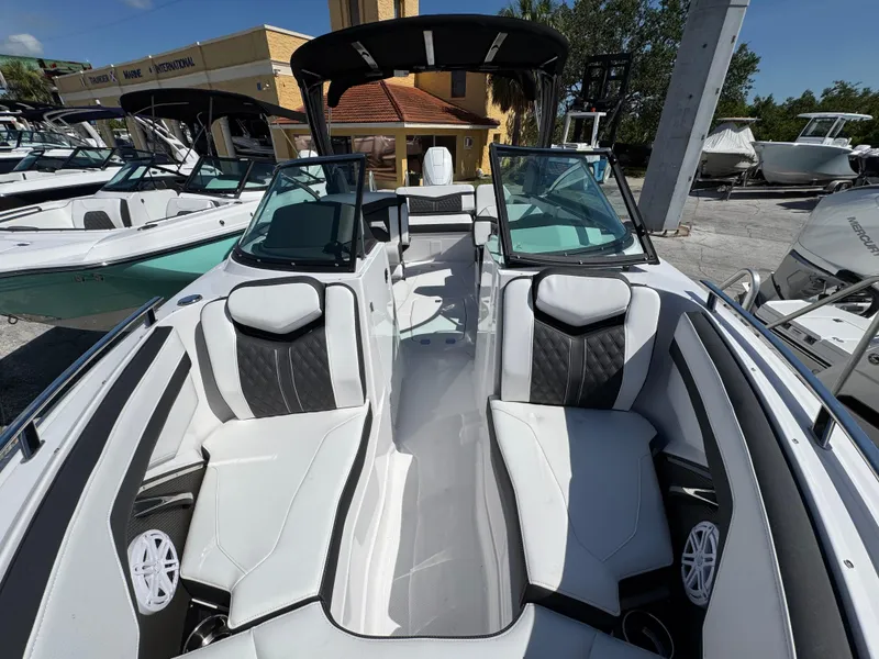 Slide: The Image of 2025 Monterey 255SS boat interior with sleek white and black seating at a marina. - 23