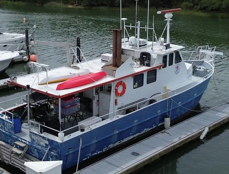Slide: The Image of Rodriquez 50 Pilothouse 1999 boat docked, featuring blue hull and red kayak on deck. - 16