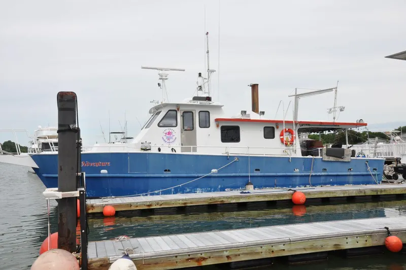 Slide: The Image of 1999 Rodriquez 50 Pilothouse boat docked at marina with orange buoys. - 2