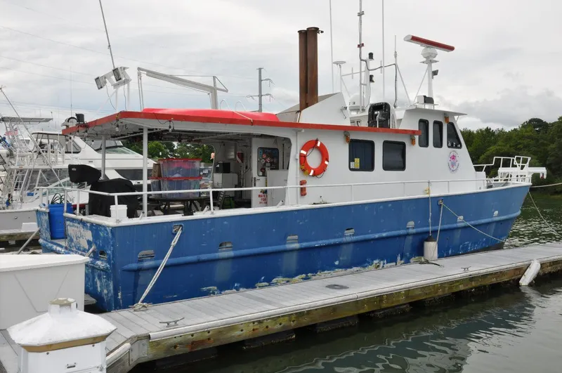 Slide: The Image of 1999 Rodriquez 50 Pilothouse boat docked, featuring blue and white exterior with red accents. - 4