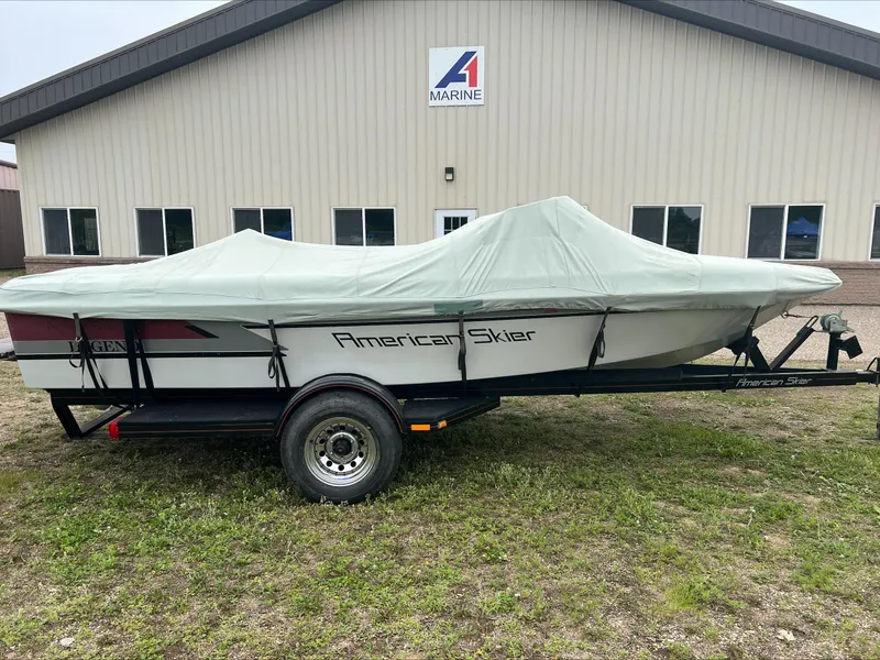 Slide: The Image of 1990 American Skier Legend boat covered, parked outside a marine building. - 3