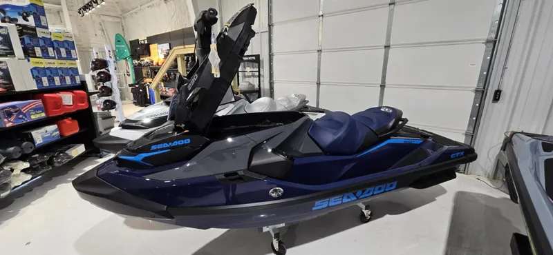 Slide: The Image of 2025 Sea-Doo GTX 230 jet ski in showroom, featuring sleek design and storage compartment open. - 2