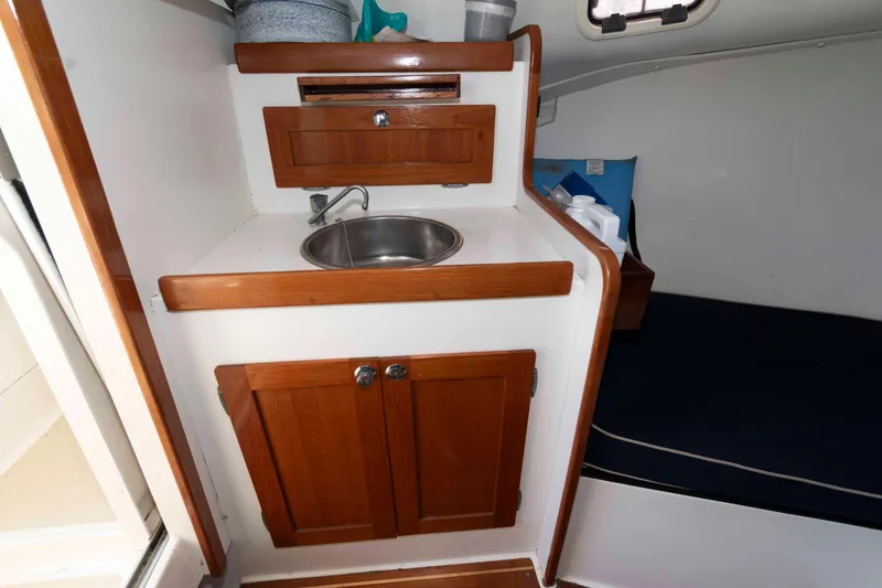 Slide: The Image of Compact kitchenette in 2005 Holby Pilot 24 boat with wooden cabinets and sink. - 13