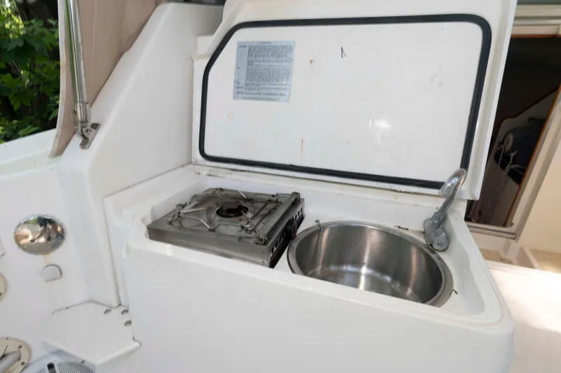 Slide: The Image of Compact kitchen setup on a 2005 Holby Pilot 24 boat, featuring a stove and sink. - 15