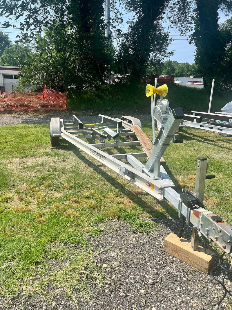 Slide: The Image of 2005 Holby Pilot 24 boat trailer on grass, surrounded by trees and fencing. - 20