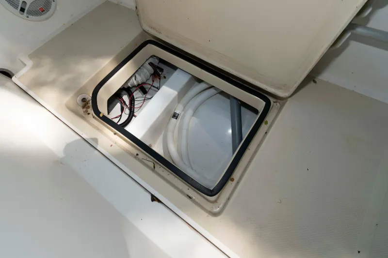 Slide: The Image of Open storage compartment on a 2005 Holby Pilot 24 boat, showing wiring and hoses. - 22