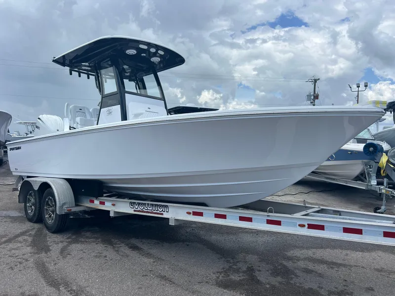 The Image of 2025 Sportsman Masters 247OE Bay Boat on trailer, under cloudy sky. - 0