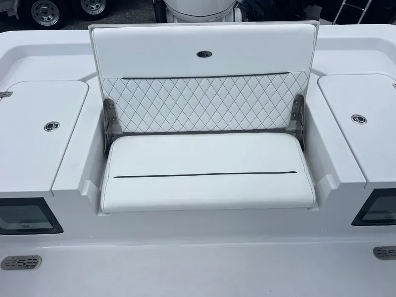 Slide: The Image of 2025 Sportsman Masters 247OE Bay Boat with white cushioned seating and storage compartments. - 20