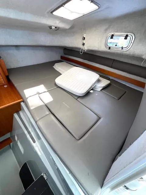 Slide: The Image of 2002 Glacier Bay 2690 Coastal Runner cabin interior with cushioned bed and porthole window. - 16