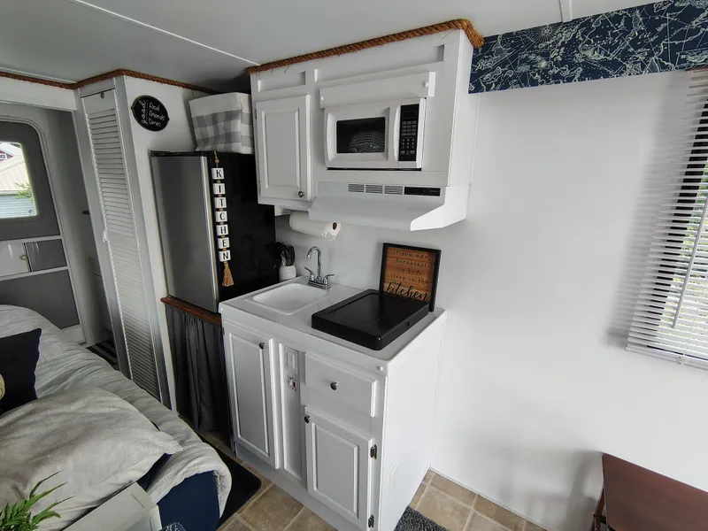 Slide: The Image of Compact kitchen in 2017 Catamaran Cruisers Lil Hobo 31 houseboat with white cabinetry and appliances. - 17