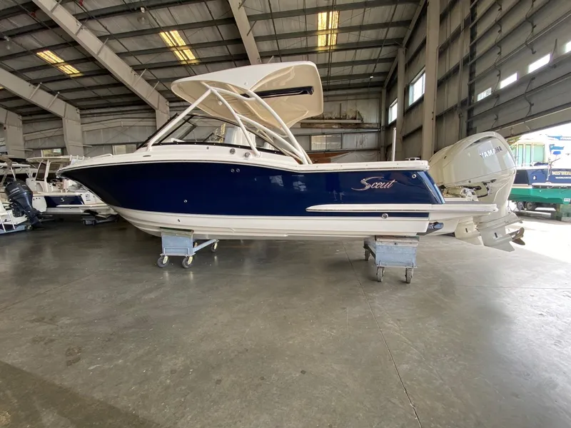 The Image of 2026 Scout 255 Dorado boat in warehouse, blue hull, Yamaha engine, elevated on stands. - 0