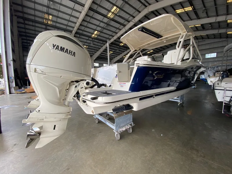 Slide: The Image of 2026 Scout 255 Dorado boat with Yamaha outboard motor in a warehouse setting. - 1