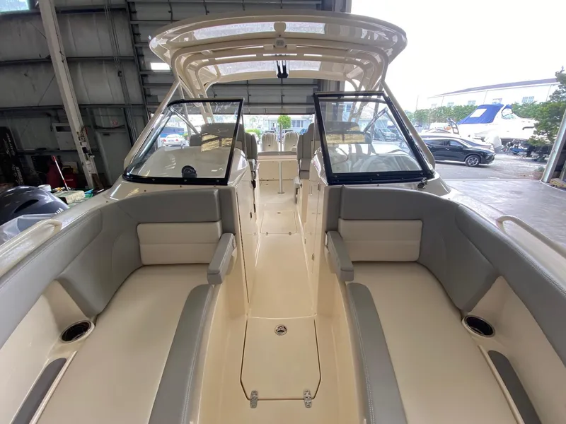 Slide: The Image of 2026 Scout 255 Dorado boat interior with seating, windshield, and open deck in a showroom. - 10