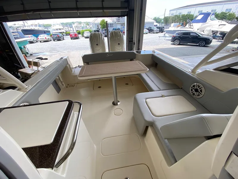 Slide: The Image of 2026 Scout 255 Dorado boat interior with seating and table in a marina setting. - 13