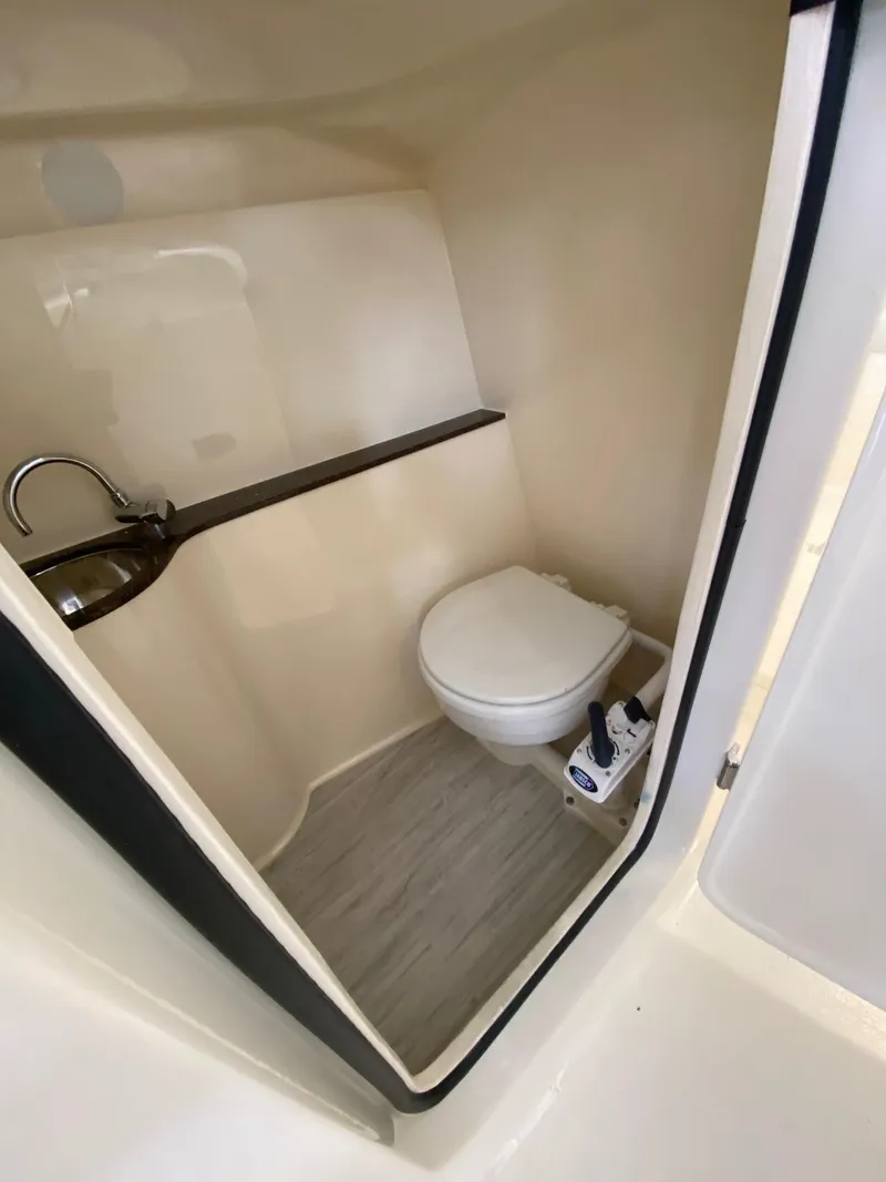 Slide: The Image of 2026 Scout 255 Dorado boat interior with compact bathroom, featuring a toilet and sink. - 14