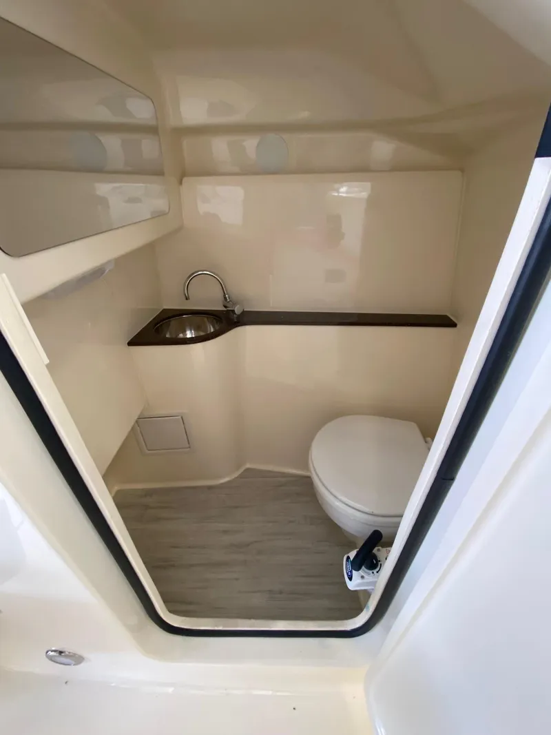 Slide: The Image of 2026 Scout 255 Dorado boat interior with compact bathroom, featuring a sink and toilet. - 15