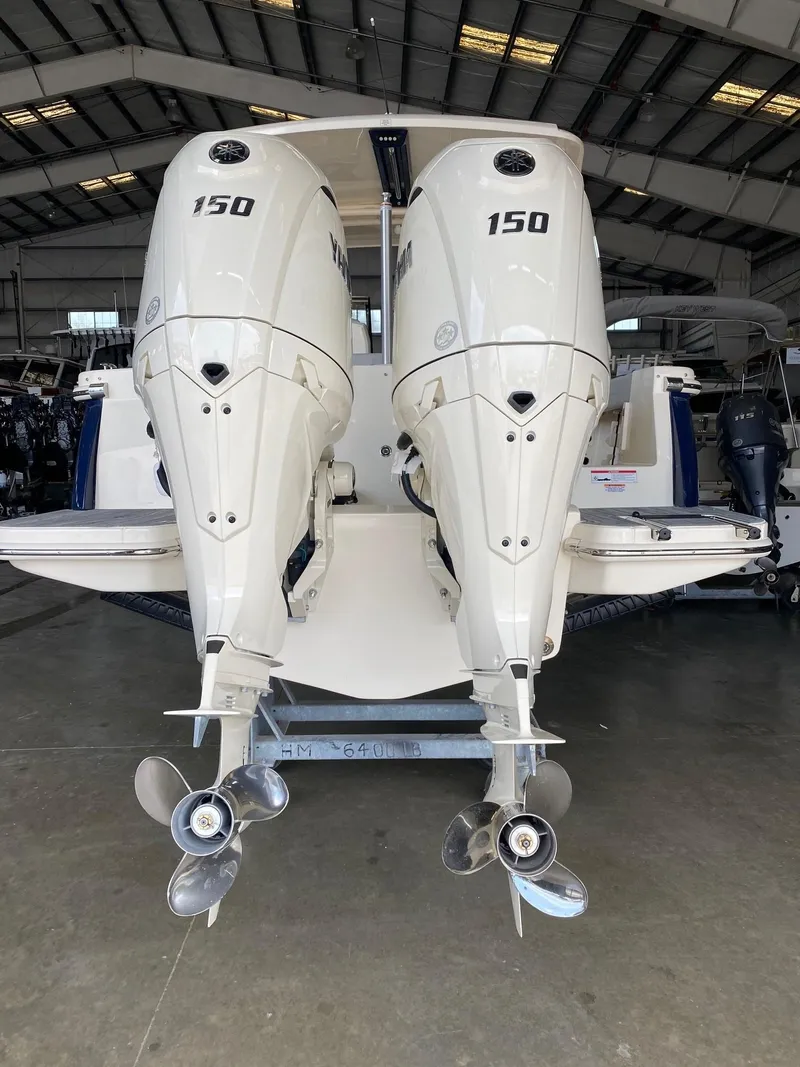 Slide: The Image of 2026 Scout 255 Dorado with dual 150 horsepower outboard engines in a boatyard. - 2
