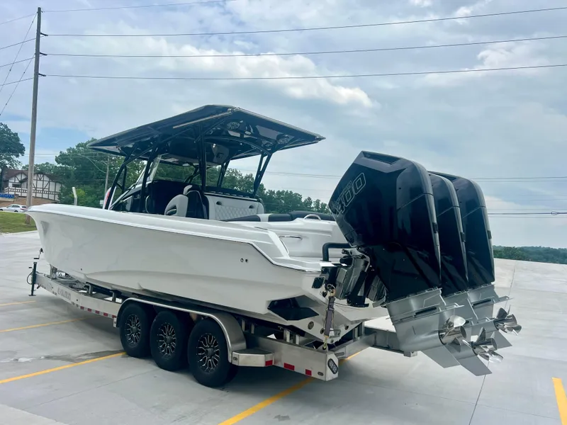 Slide: The Image of 2025 Nor-Tech 340 Sport Center Console boat on trailer with triple outboard engines. - 45