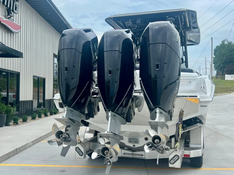 Slide: The Image of 2025 Nor-Tech 340 Sport Center Console with triple outboard engines, parked near a building. - 47
