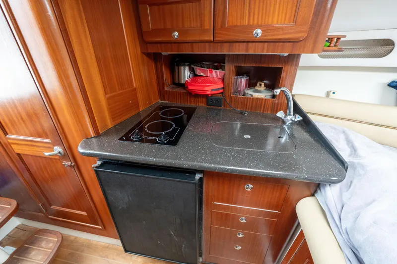Slide: The Image of 2007 Pro-Line 35 Express boat interior kitchen with stove, sink, and wooden cabinetry. - 17