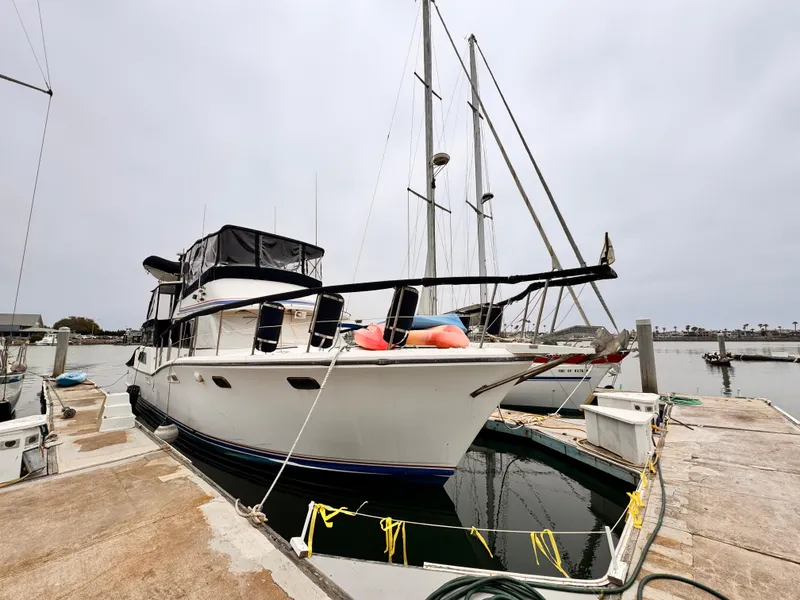 The Image of 1985 Symbol 51 Cockpit Motor Yacht docked at marina, overcast sky. - 0