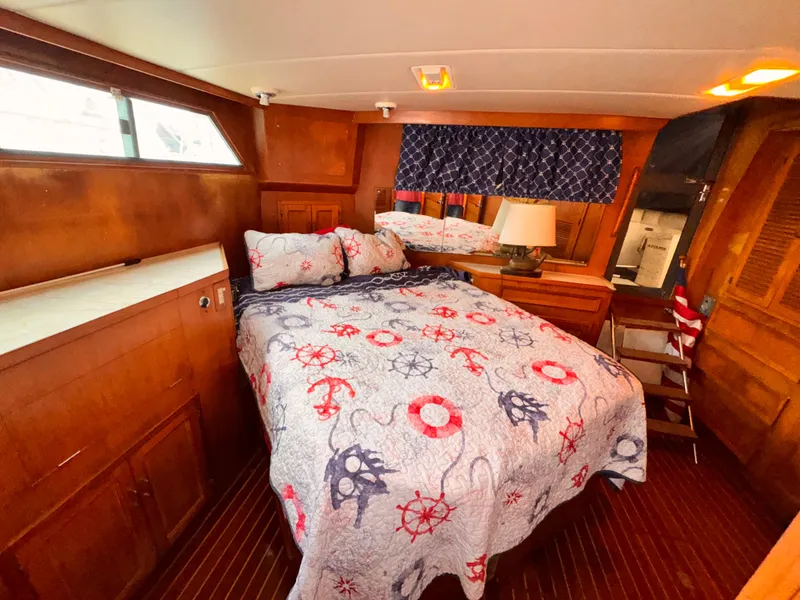 Slide: The Image of 1985 Symbol 51 Cockpit Motor Yacht bedroom with nautical-themed bedding and wooden interior. - 12