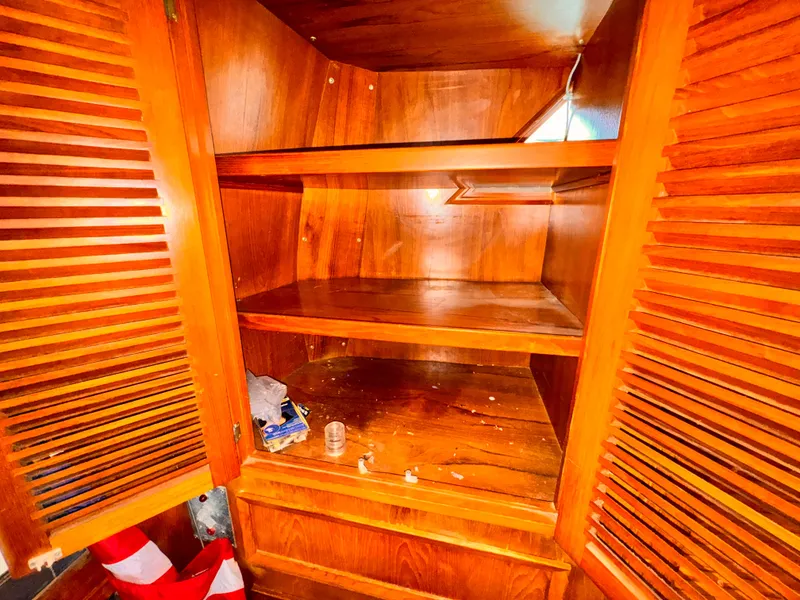 Slide: The Image of Wooden cabinet interior on 1985 Symbol 51 Cockpit Motor Yacht, featuring shelves and louvered doors. - 13
