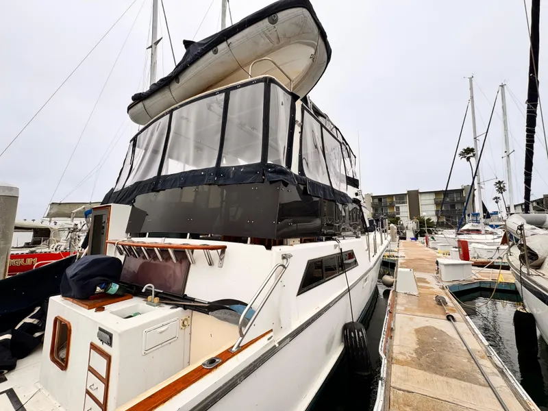 Slide: The Image of 1985 Symbol 51 Cockpit Motor Yacht docked at marina, featuring enclosed upper deck and inflatable boat. - 19