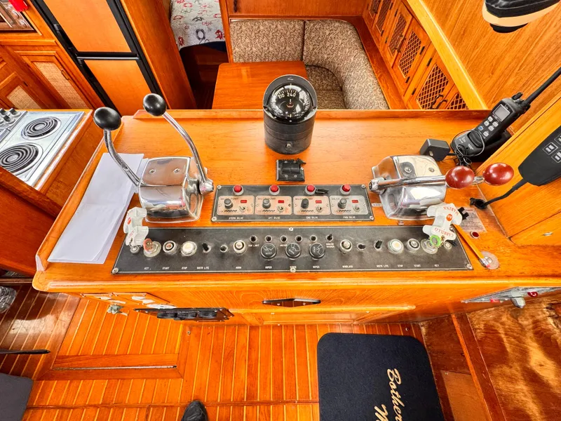 Slide: The Image of 1985 Symbol 51 Cockpit Motor Yacht helm with controls and compass, featuring wood finish. - 6