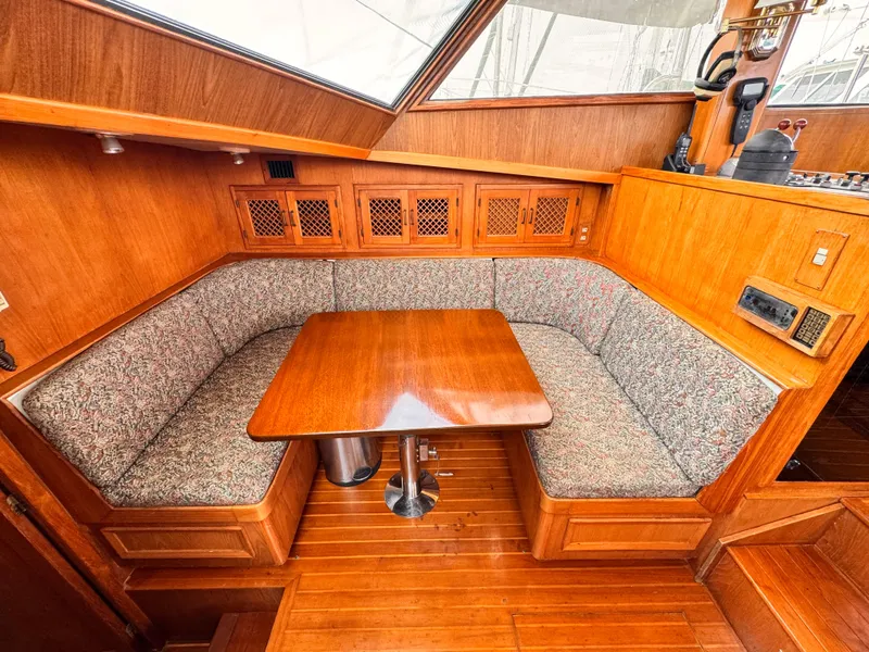 Slide: The Image of 1985 Symbol 51 Cockpit Motor Yacht interior with wooden dining area and cushioned seating. - 9