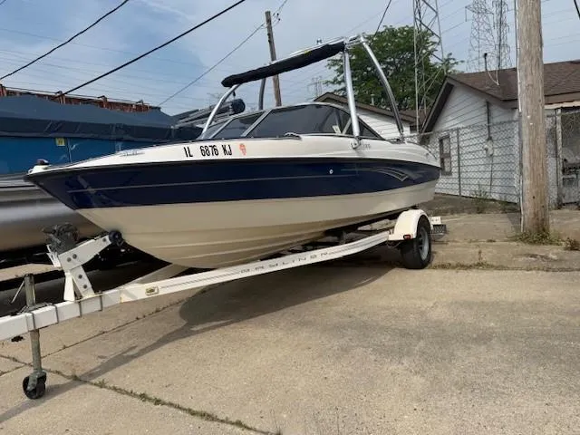 Slide: The Image of 2010 Bayliner 185 Runabout boat on trailer, covered with blue tarp, parked outdoors. - 3