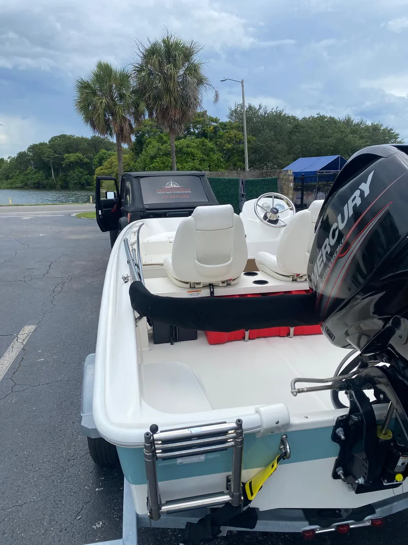 Slide: The Image of 2018 Boston Whaler 150 Super Sport boat with Mercury engine on trailer, near palm trees. - 10