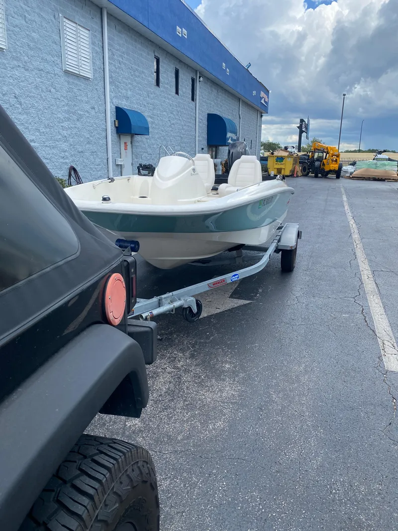 Slide: The Image of 2018 Boston Whaler 150 Super Sport boat on trailer, parked outside a building. - 9